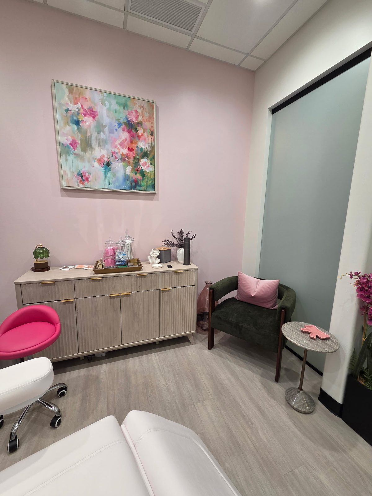 Treatment suite at Infinite Glow with the pink feature wall and a seat for a guest